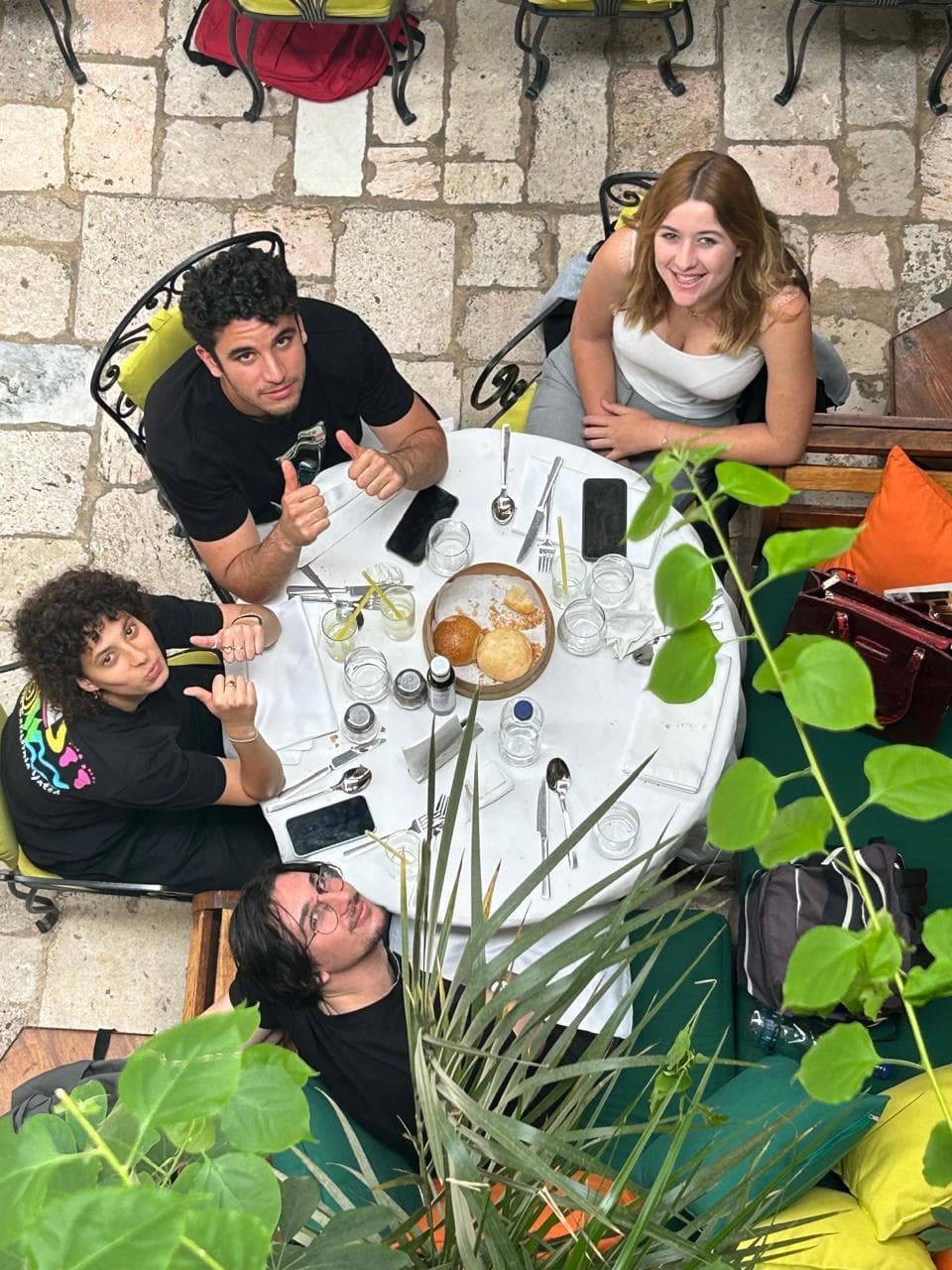 People gathered around an outdoor table beside plants.