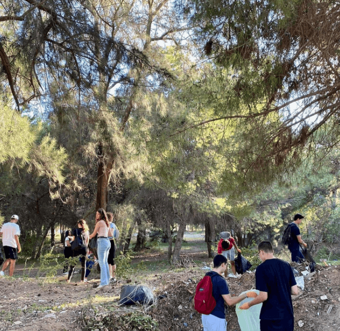 People walking and gathering among trees outdoors.