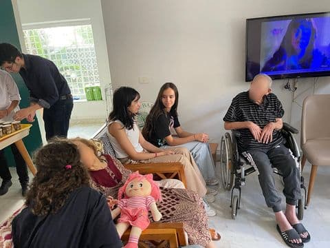 People sitting together in a room beside a television.
