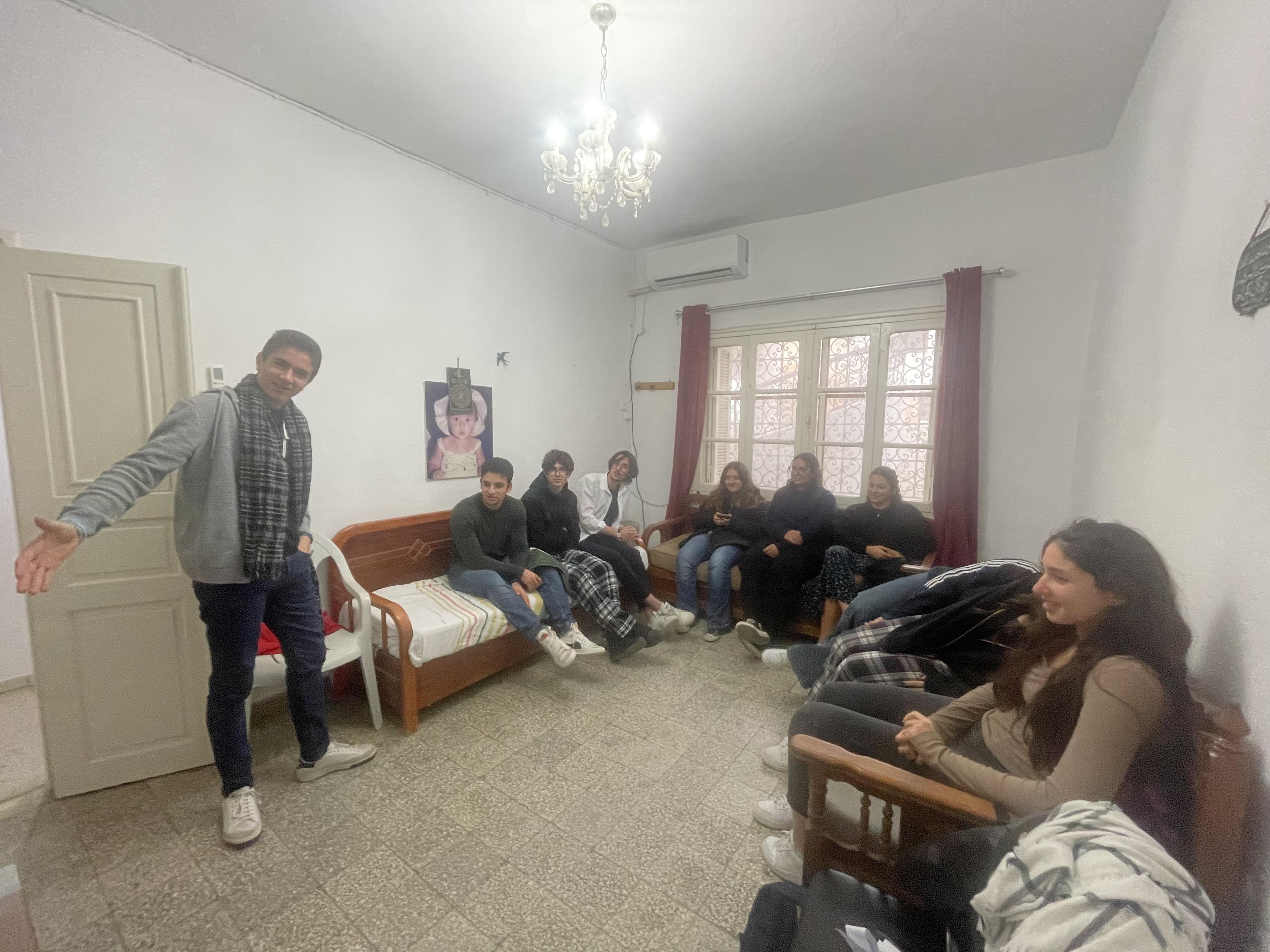 People gathered in a bright room with chairs and a sofa.
