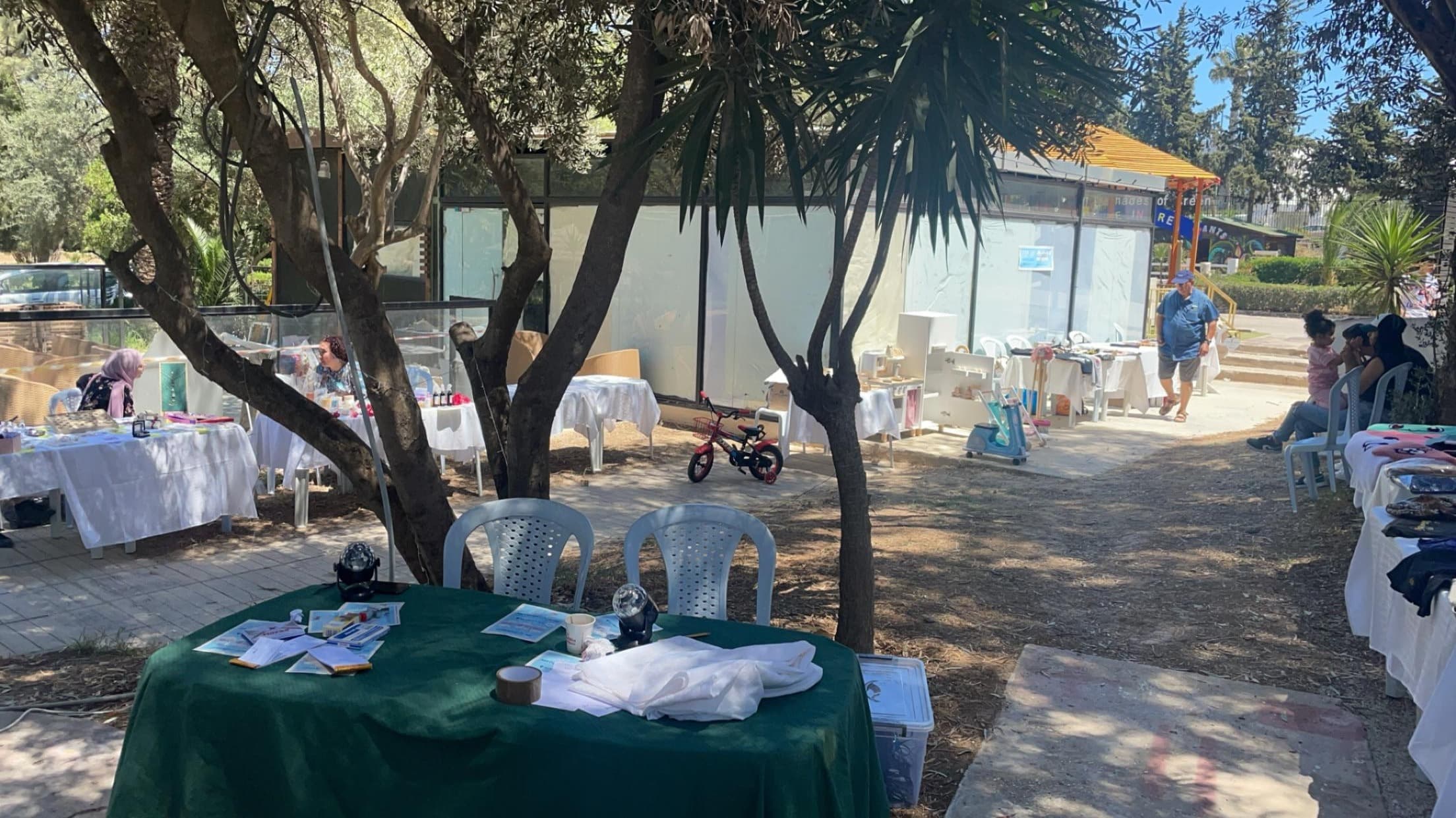 Tables arranged outdoors beneath trees.
