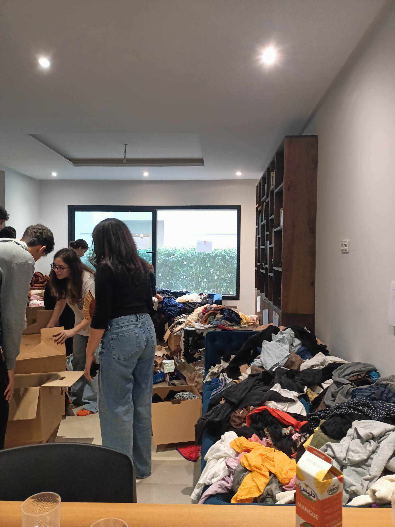 People sorting clothing and boxes in a room.