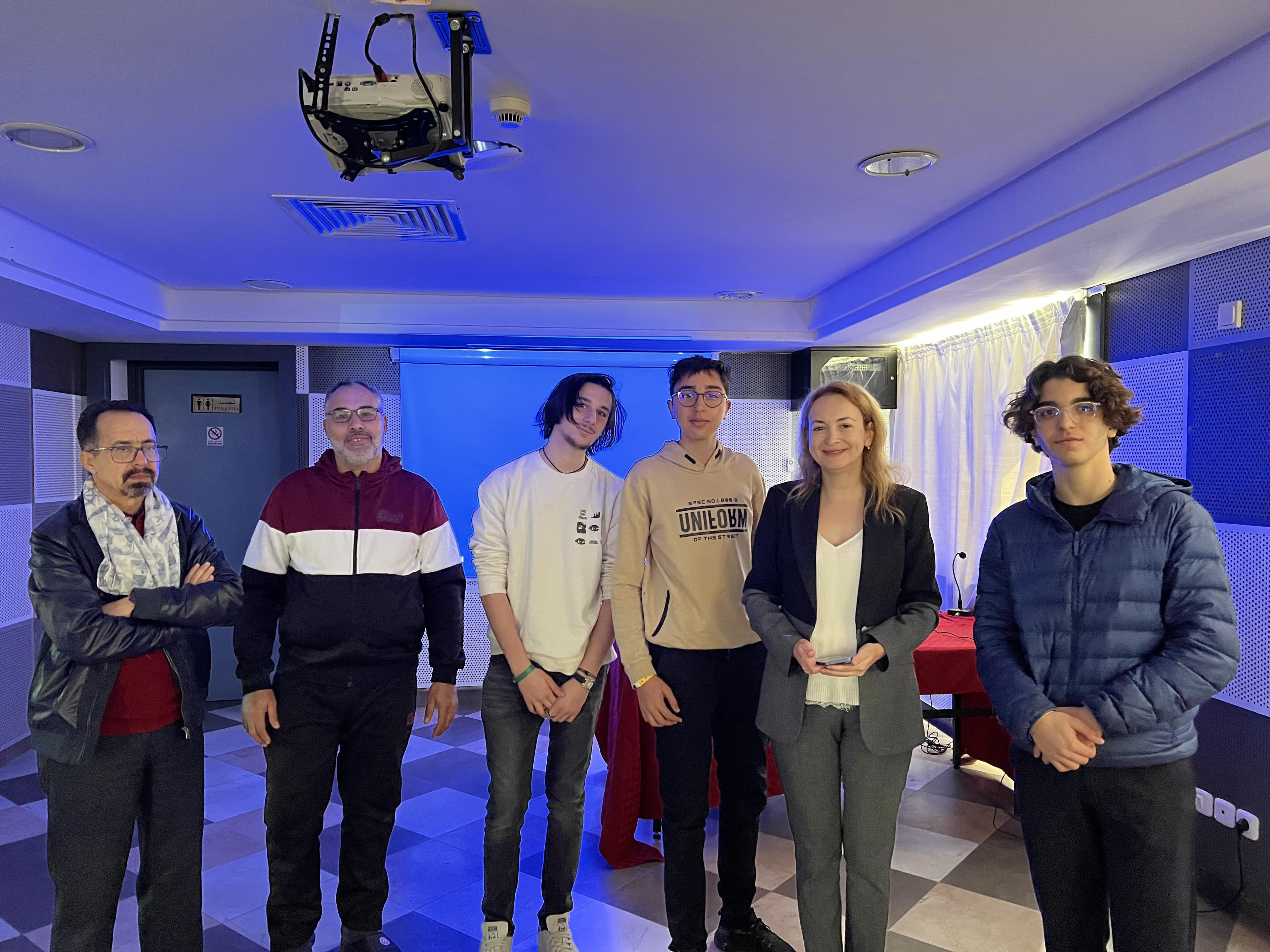 A group posing together in a room with blue lighting.