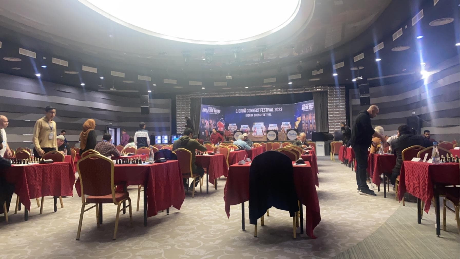 Rows of tables and chairs set up with chessboards in a large hall.
