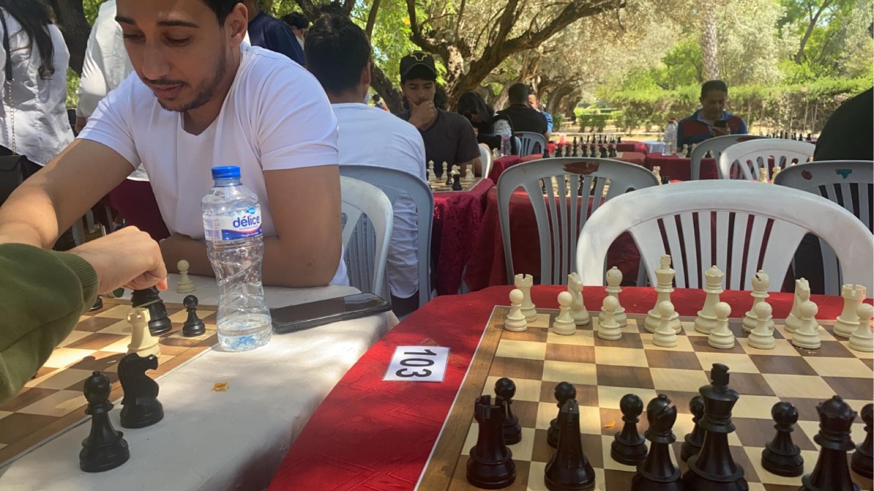 Chessboards and players at tables in an outdoor setting.
