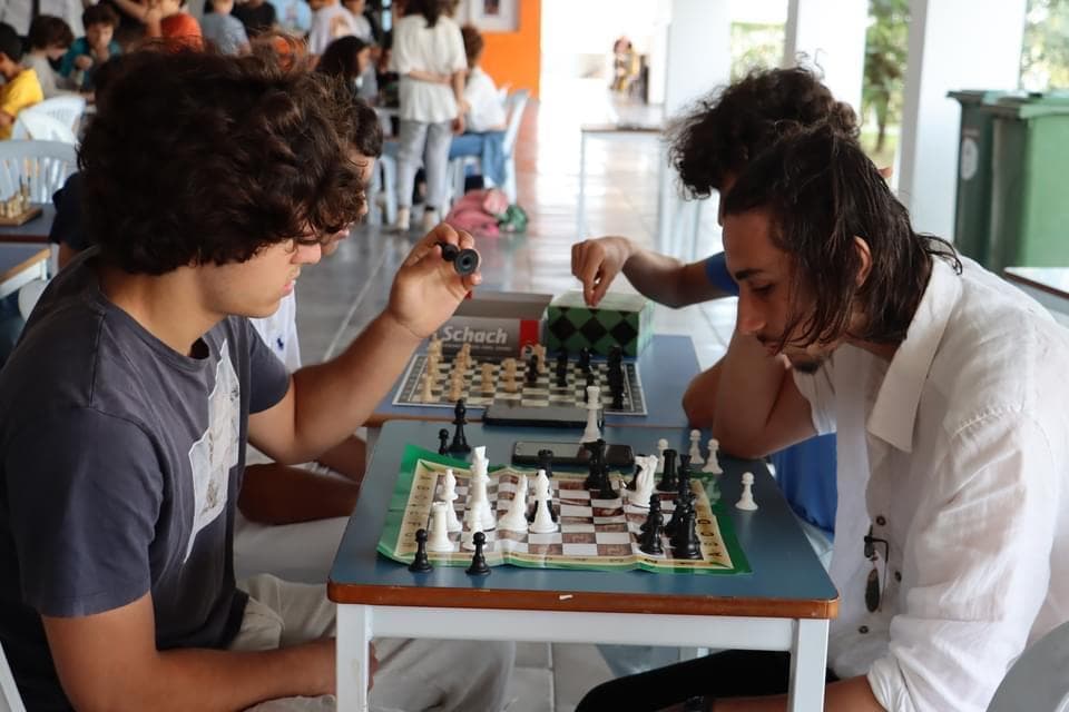 Two people playing chess across a small table.