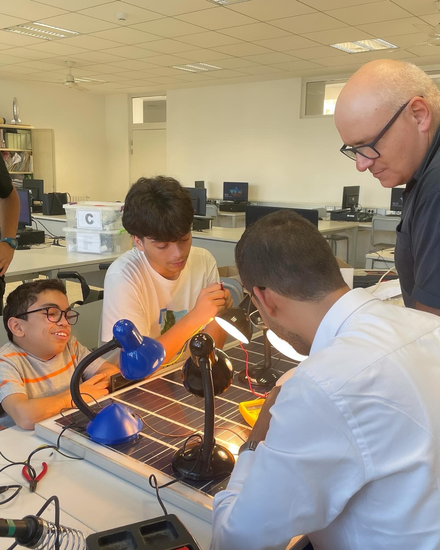 Several people examining equipment on a workshop table.