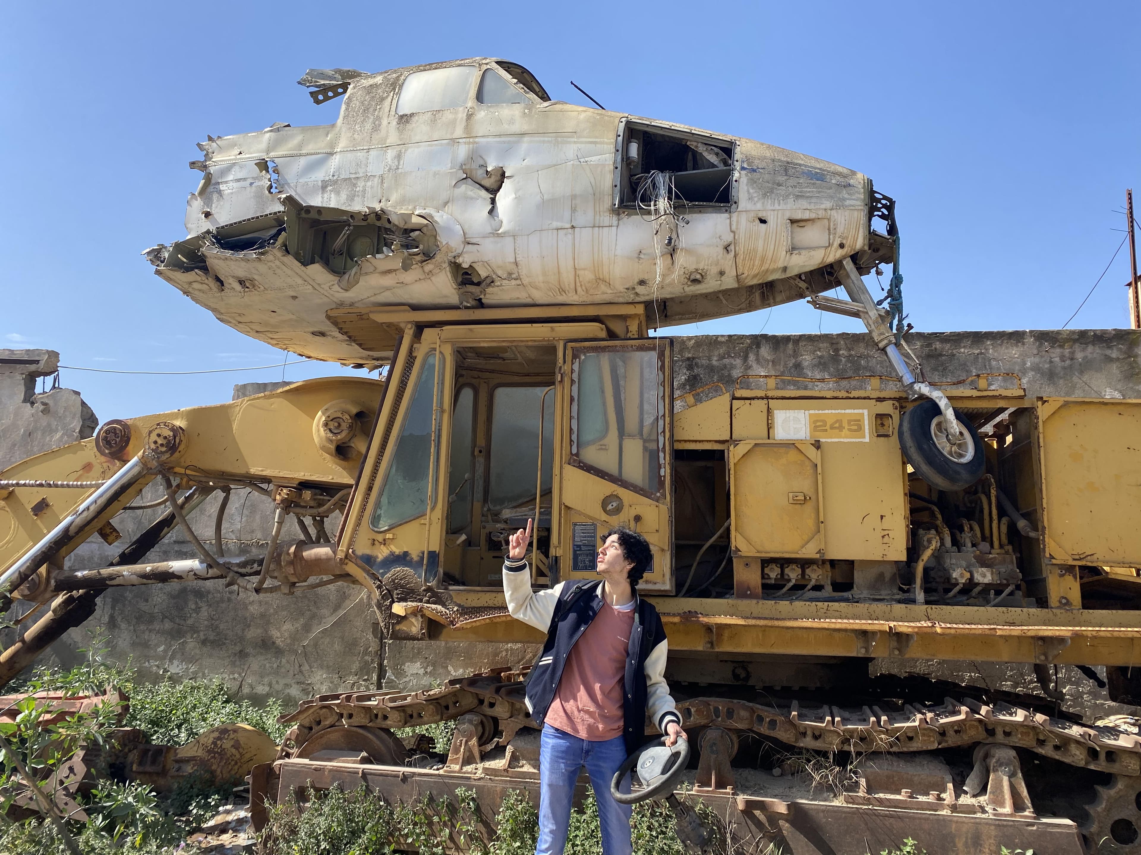 A person standing beside heavy machinery in an outdoor yard.