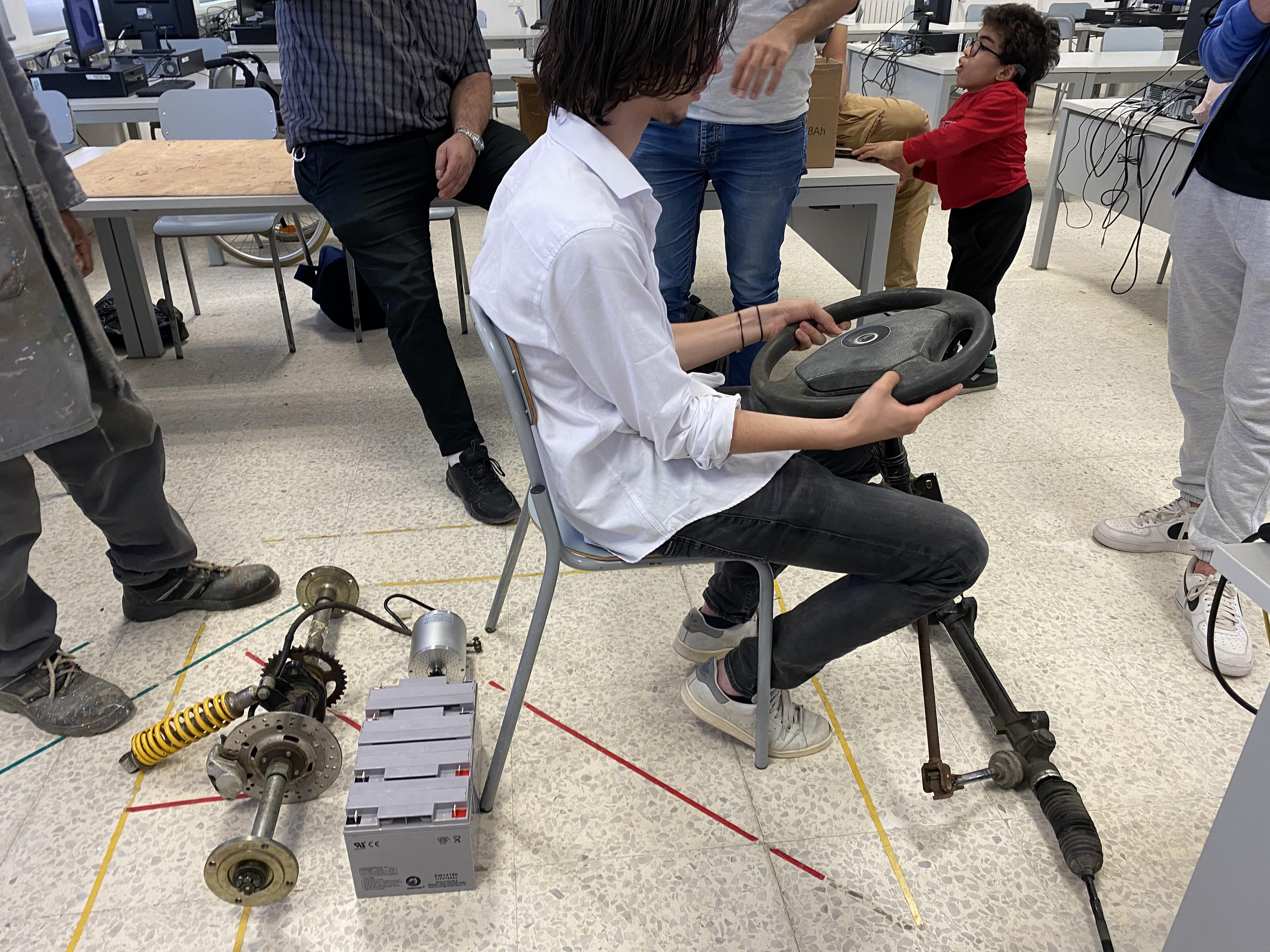 A person seated at the steering wheel of a metal vehicle frame.