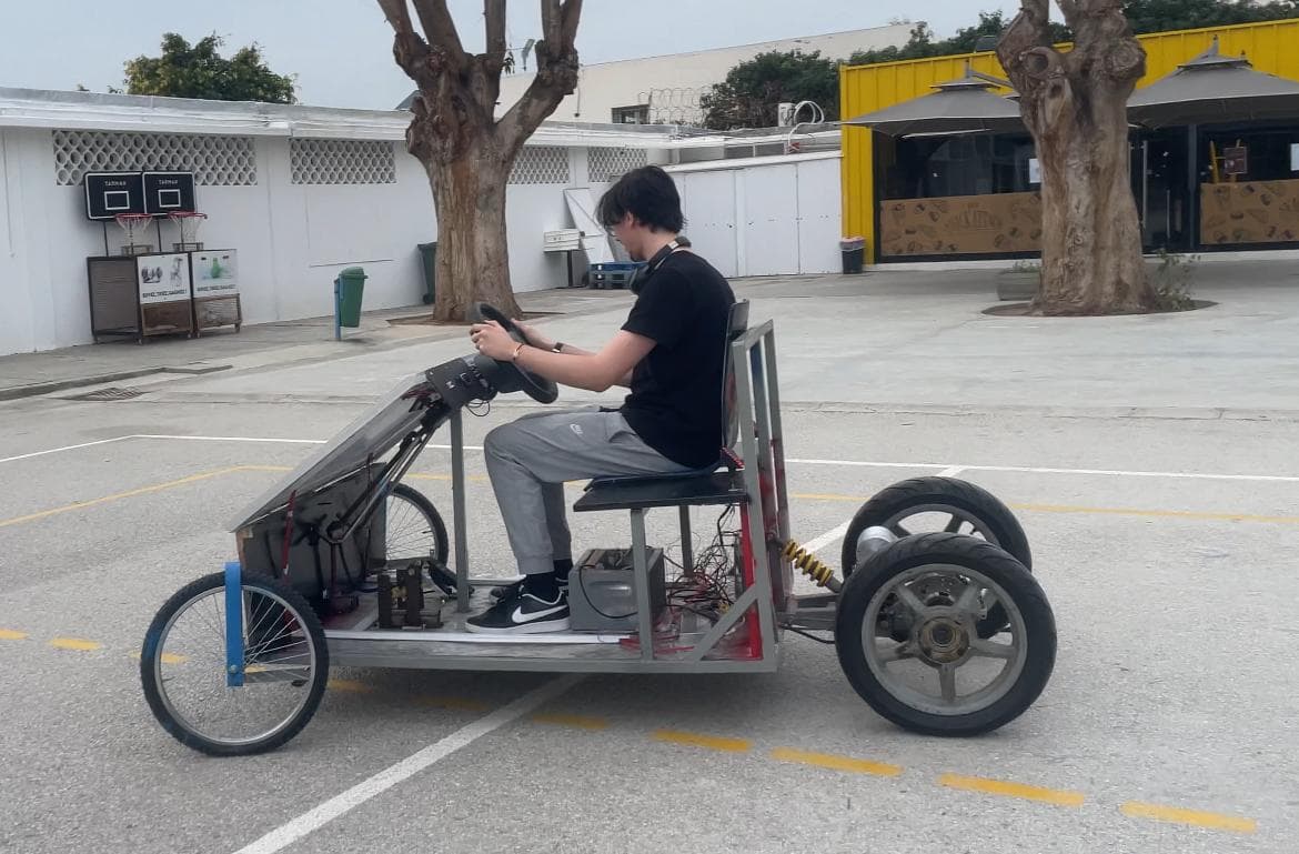 A person seated in a small open-frame vehicle outdoors.