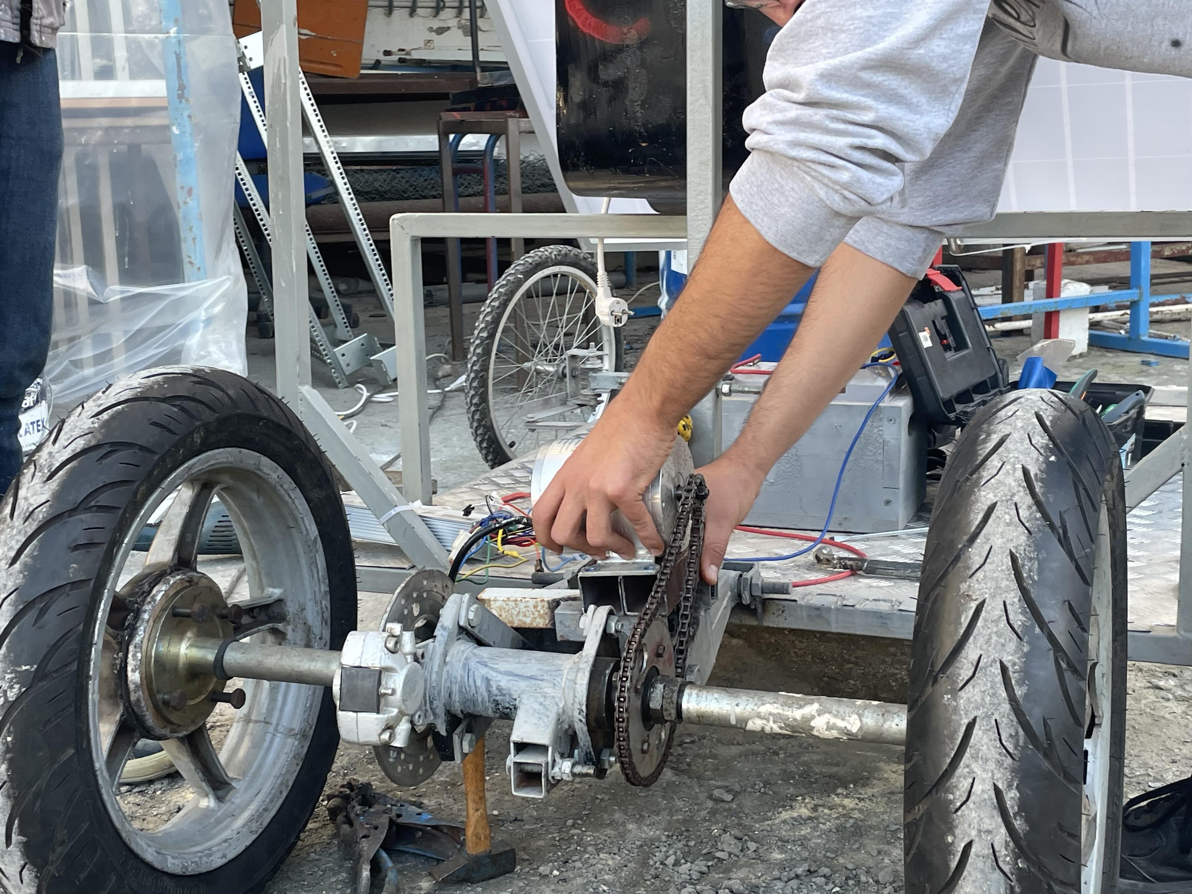 Hands adjusting a mechanical assembly between two wheels.