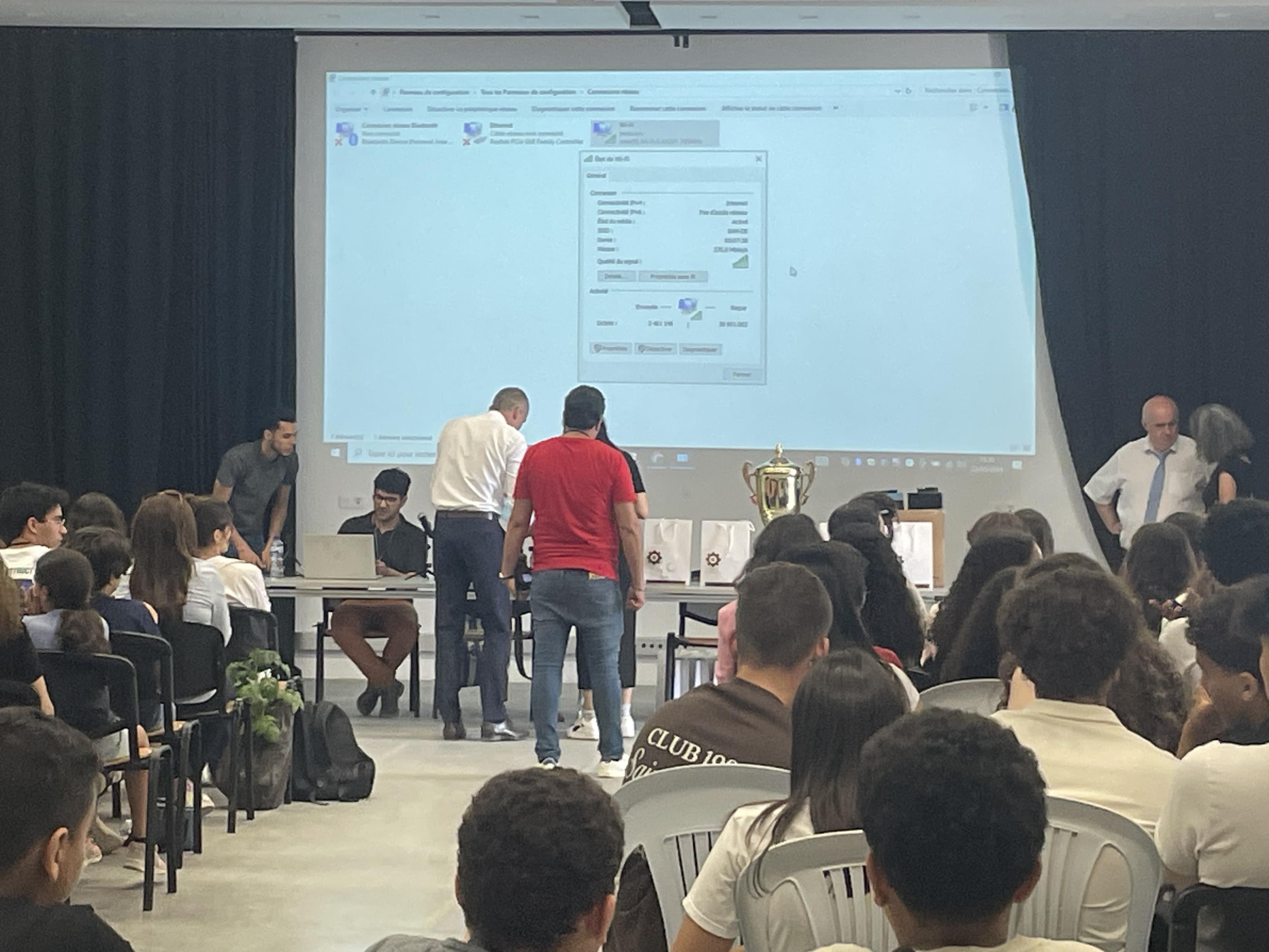 An audience watching a projected presentation in a classroom.