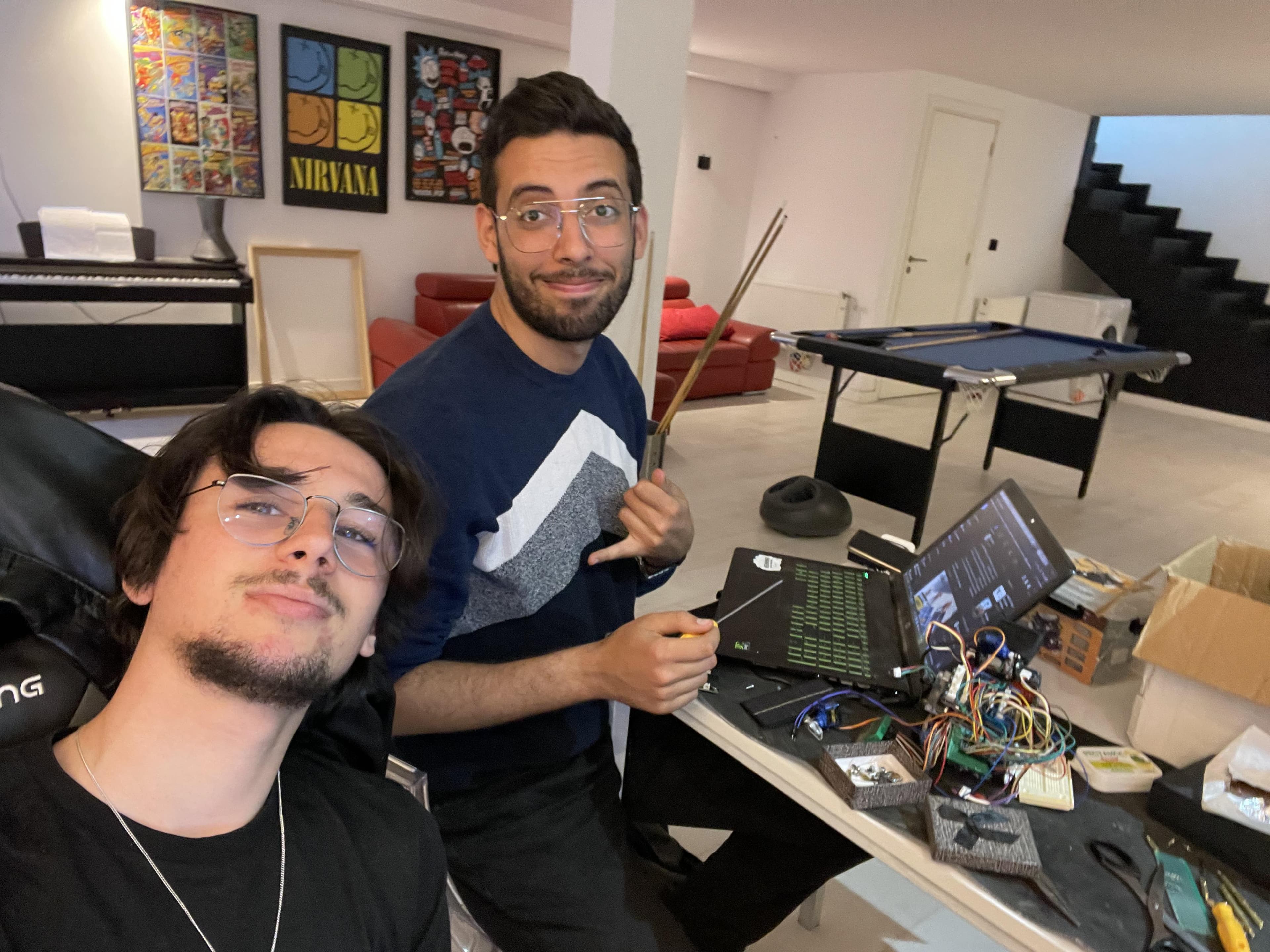 Two people beside electronic equipment on a workbench.