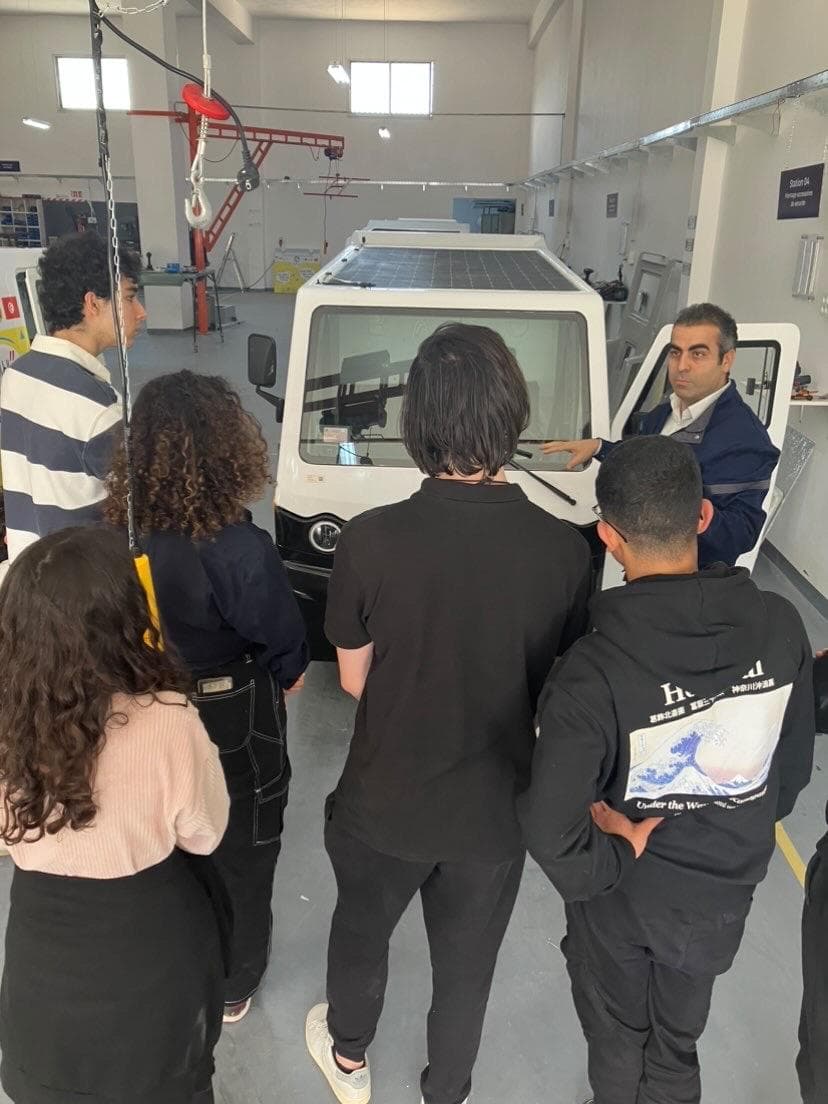 People standing together in a workshop beside equipment.