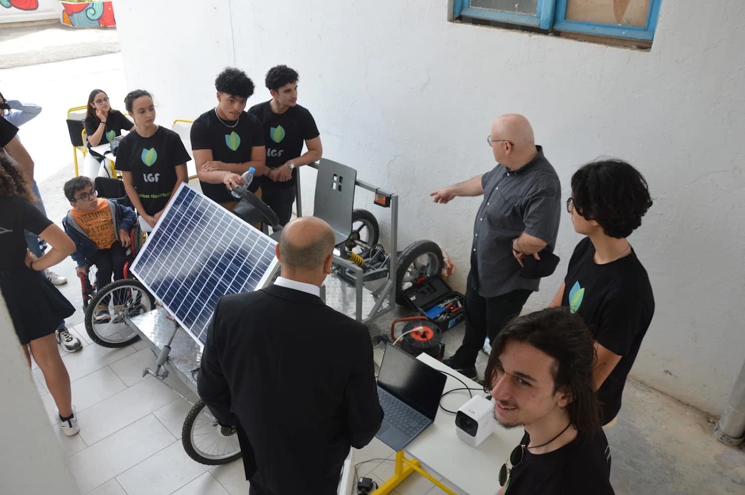 People standing around the solar-electric car, with a laptop beside the prototype