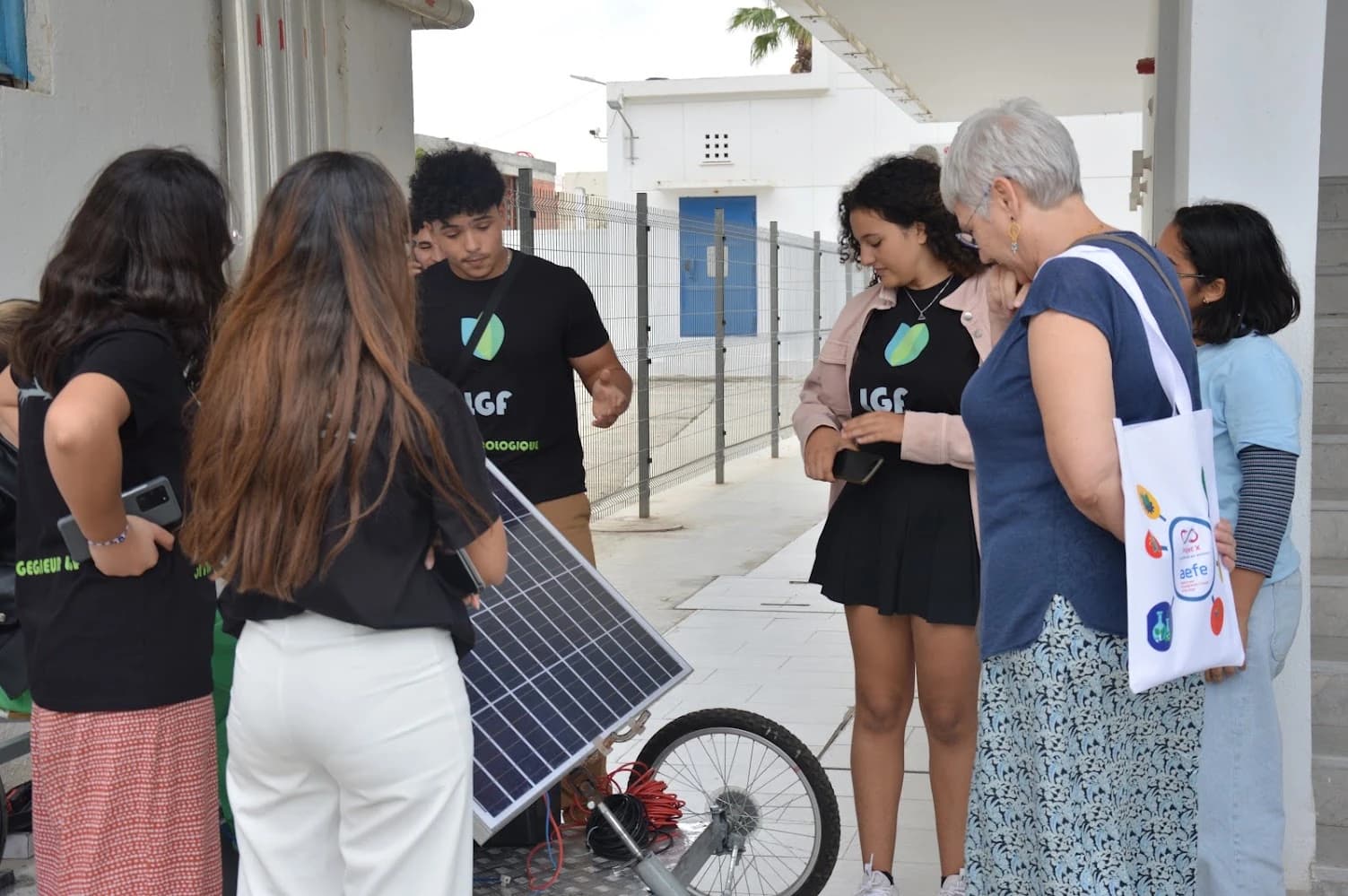 A group gathered around the solar panel and front wheel of the vehicle prototype