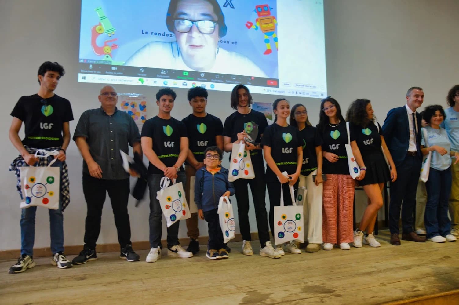 A group on a stage holding a glass trophy and Projet X gift bags