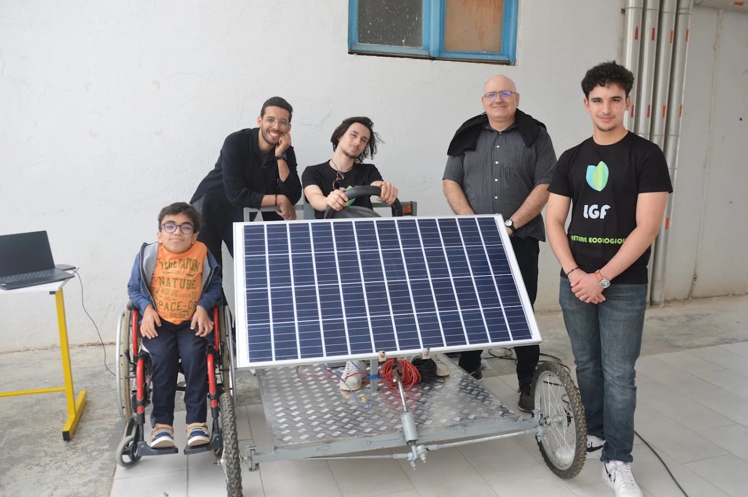 A group behind the solar panel at the front of the vehicle prototype