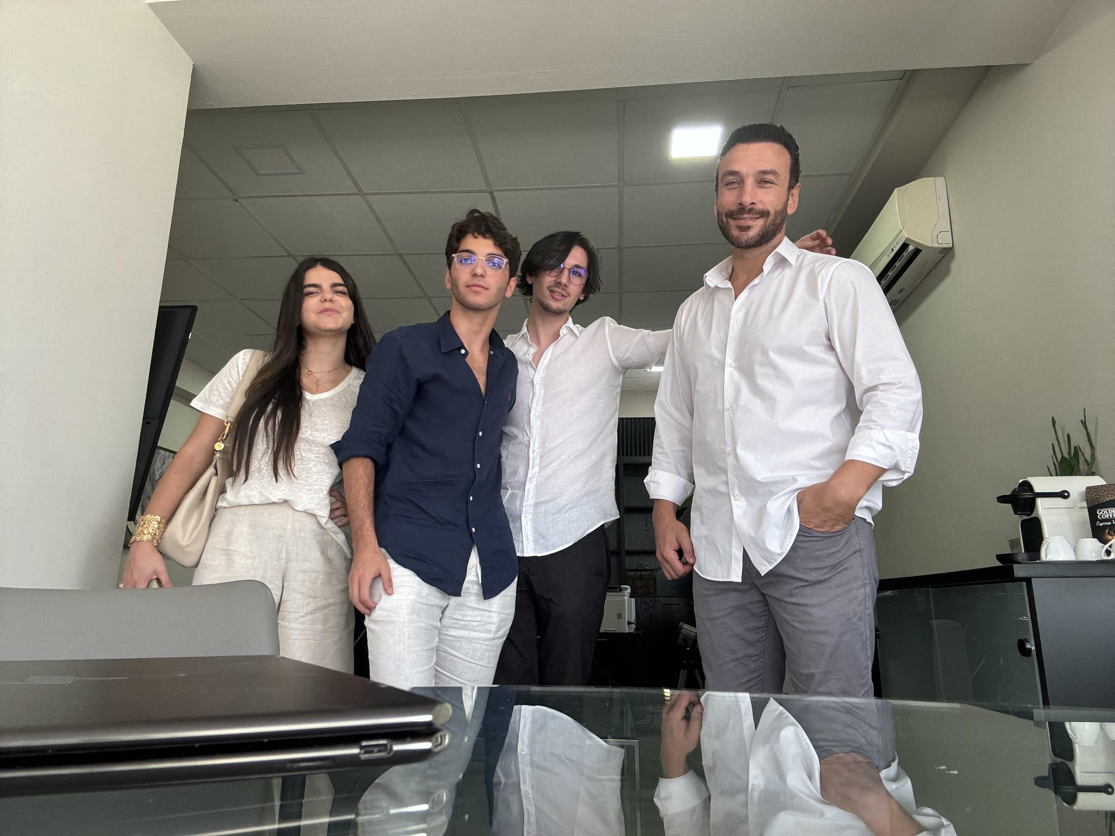 Four people posing beside a table in an office.