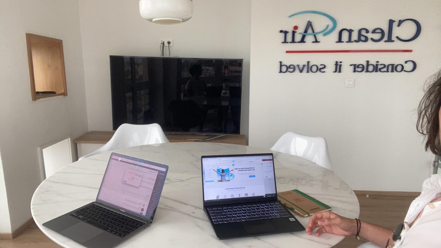 Two laptops open on a meeting-room table.