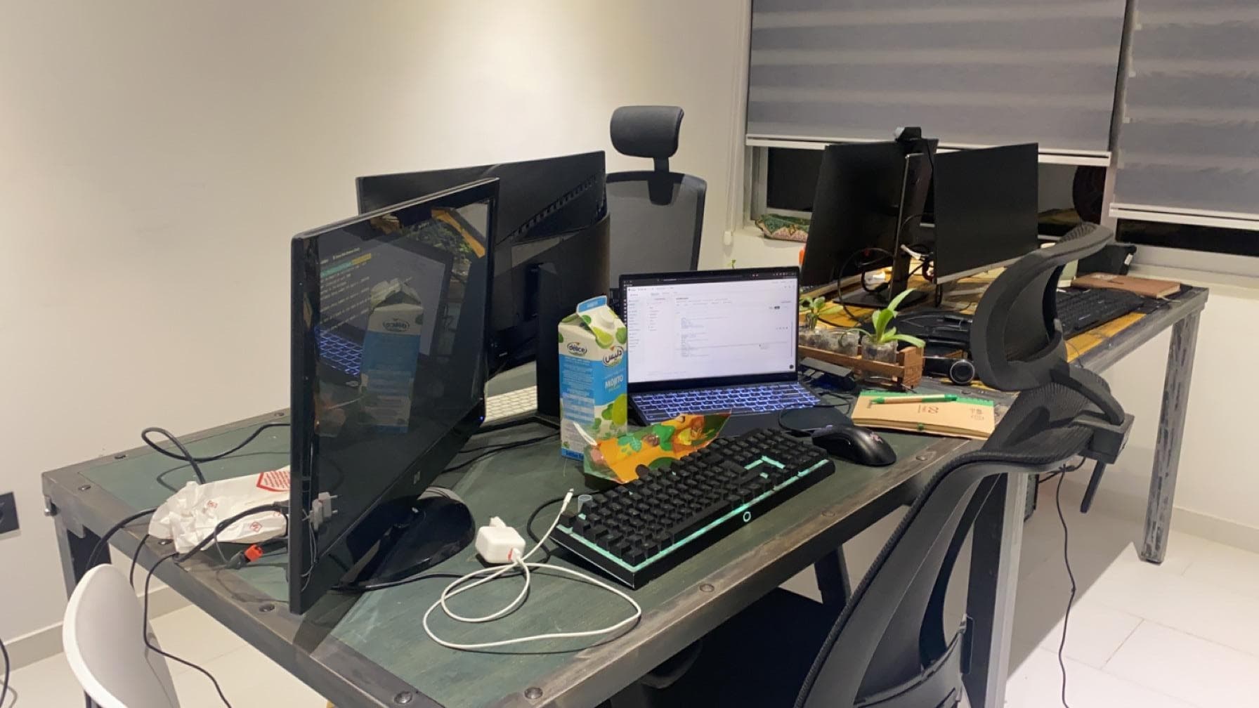 A workstation with multiple screens, a laptop and a keyboard.