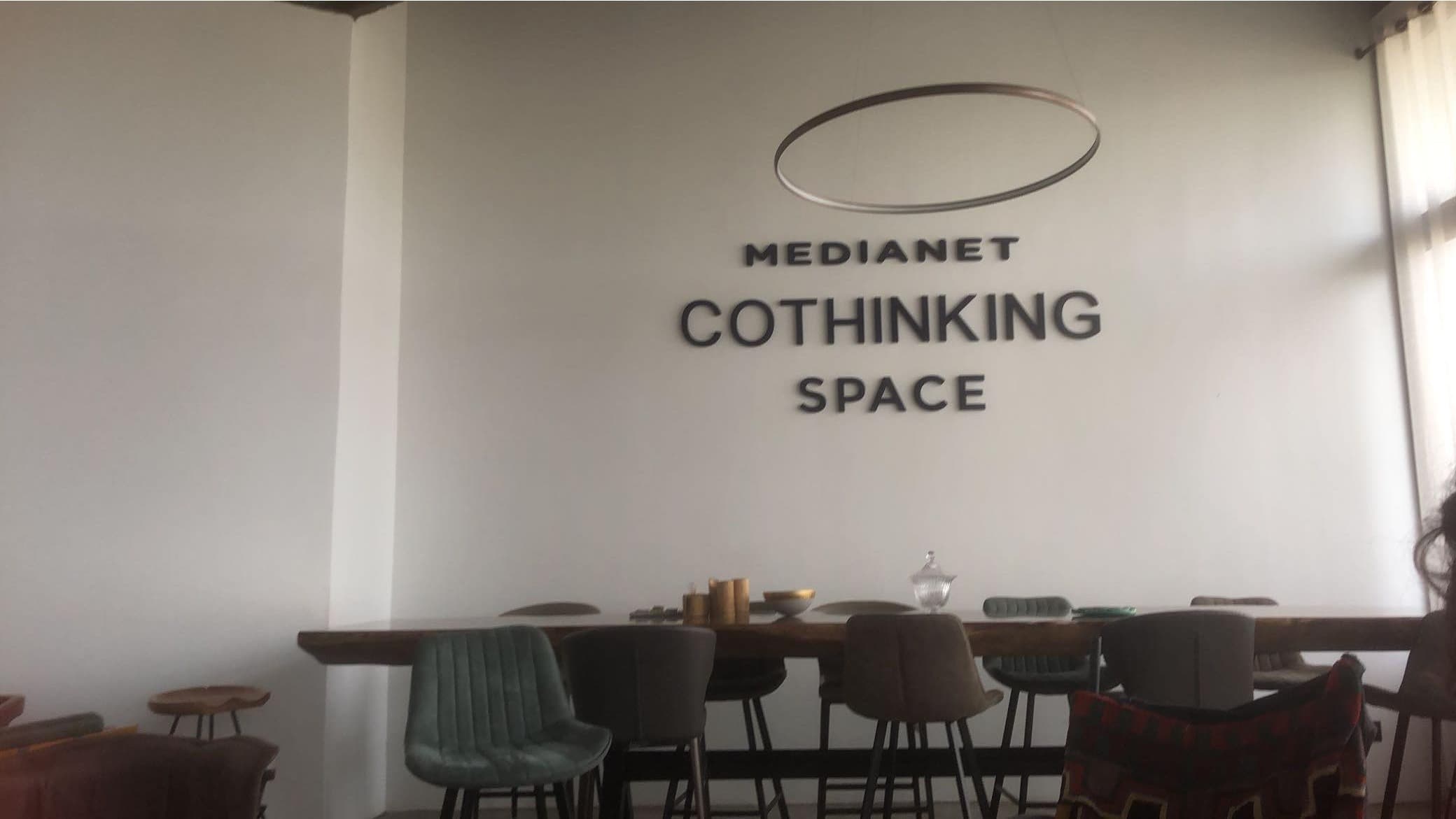 A meeting area with a table, chairs and a wall sign.
