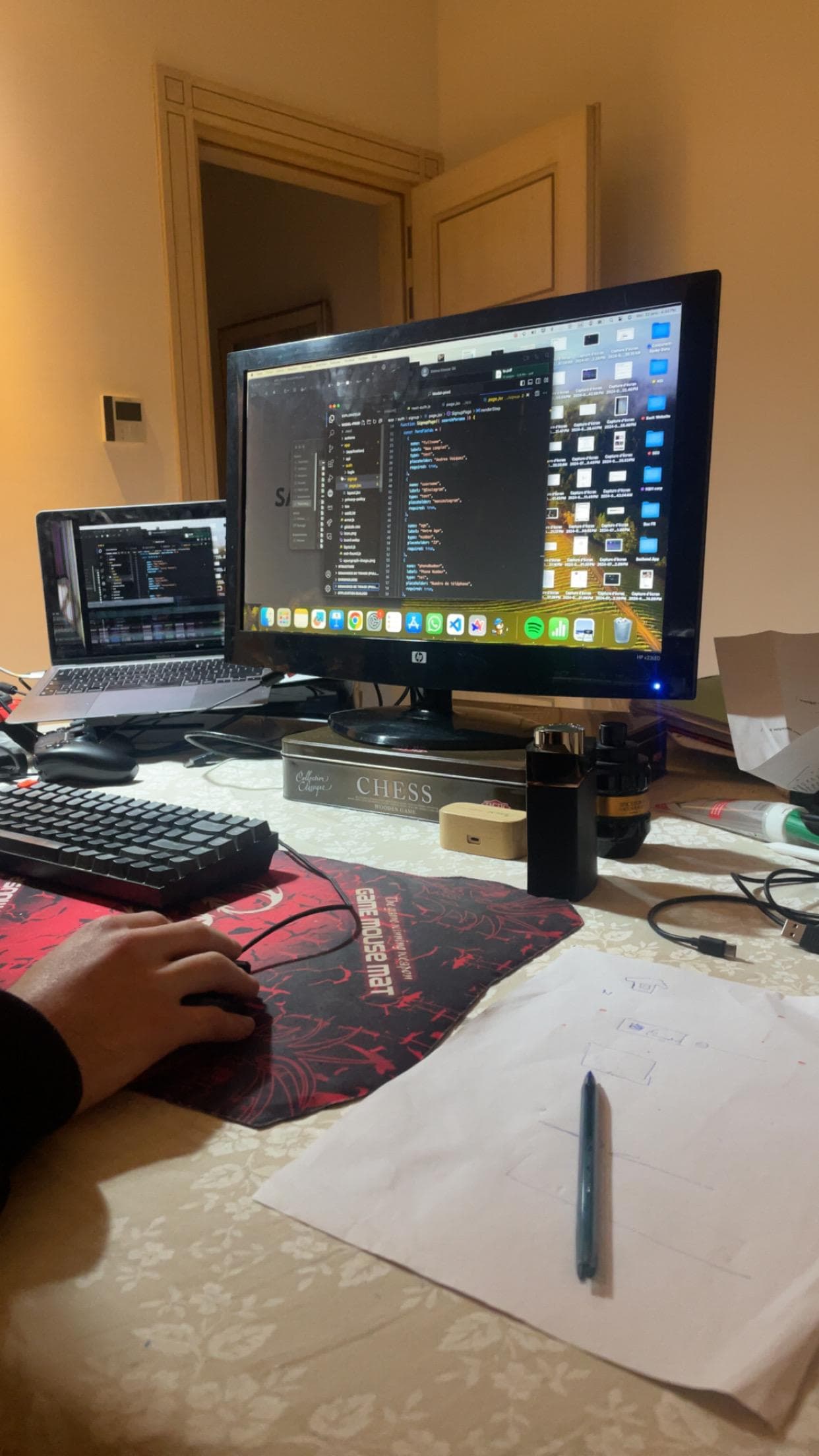 A coding desk with a laptop, monitor and handwritten notes.