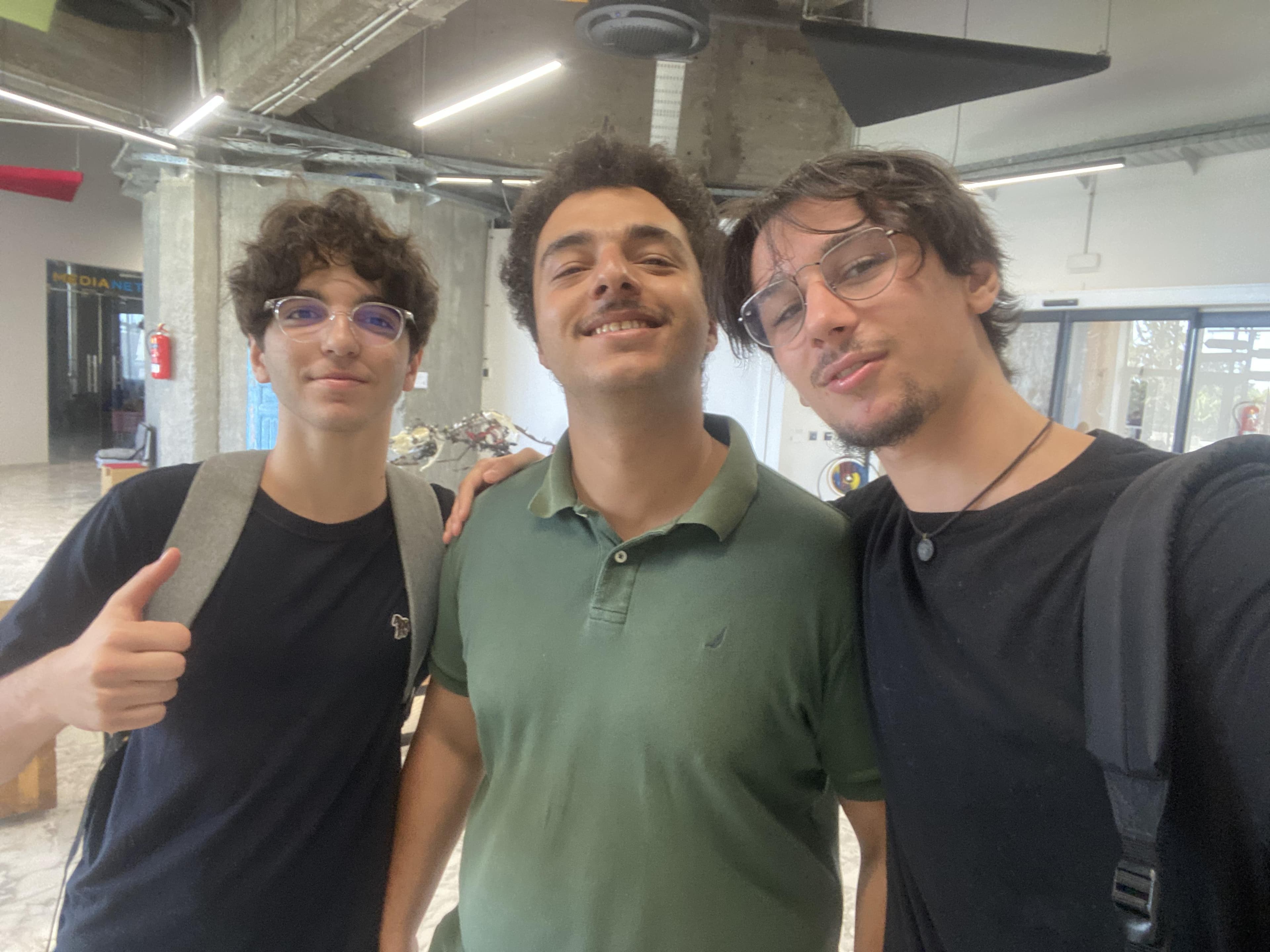 Three people posing together in an indoor workspace.